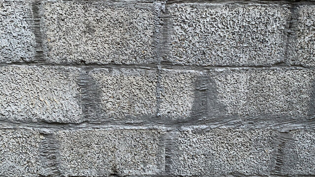 Close-up view of a rugged, textured gray concrete block wall, revealing the intricate patterns and rough surface of the durable cinder blocks, perfect for backgrounds and architectural design.