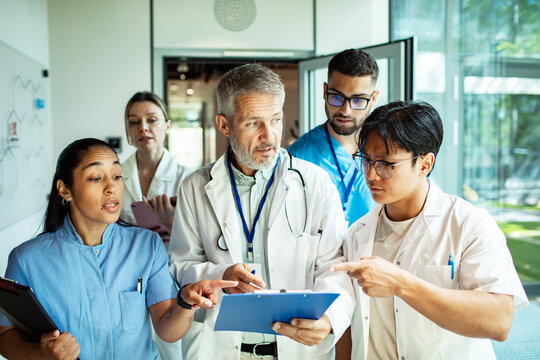 Doctors and nurses discussing patient chart in hospital corridor
