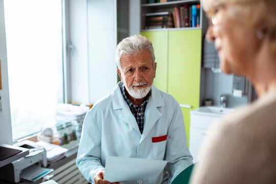 Senior doctor consulting elderly patient in medical office