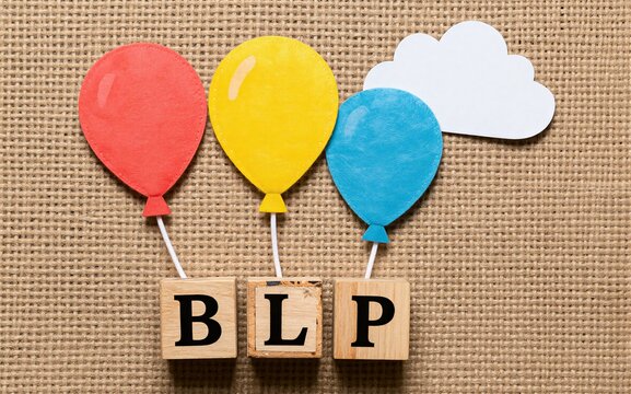 Colorful balloons float above wooden blocks spelling BLP on a