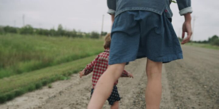 Mother and toddler walking together on a country road
