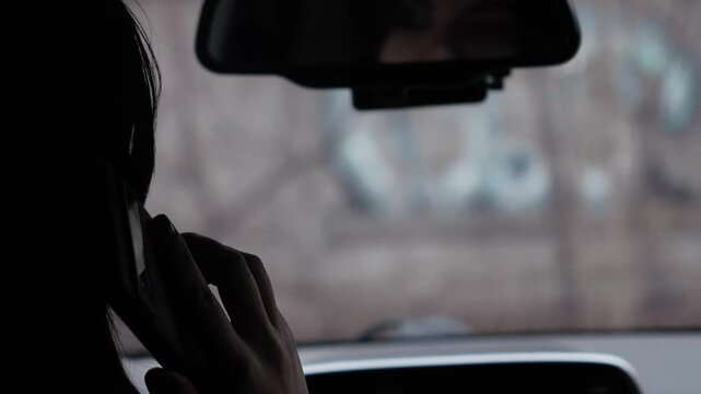 Woman driver talking on the phone behind the wheel of a parked car. Responsibility, background, screen saver, close-up, rear view without face, atmospheric shot