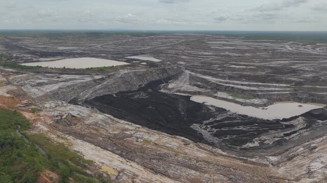 Aerial view of a vast coal mine and blackened excavation pits filled with coal