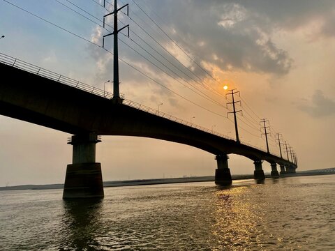 Beautiful sunset over Jamuna river and the Jamuna Bridge. Colorful reflections in the water. Sunset on the river bridge. Railway bridge at beautiful sunset. Sunset through a bridge.