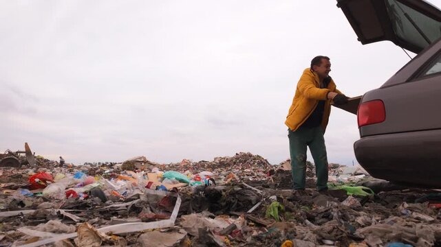 Frustrated man in a yellow jacket illegally dumping a wooden board from his car into a large, polluted city landfill, contributing to environmental contamination and waste problems