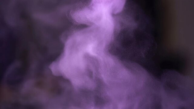 Purple powder explosion forming abstract vibrant pattern concept. Purple smoke or powder cloud swirling in dark background with soft and ethereal texture