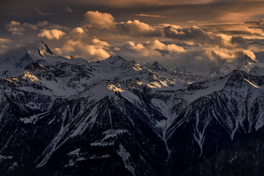 Alp Sunset. Foggy cloud morning in Swiss Alps, early morning in the mountain during violet pink twilight, hills in the clouds. End of the night. Winter landscape in Switzerland from Gemmi Pass.