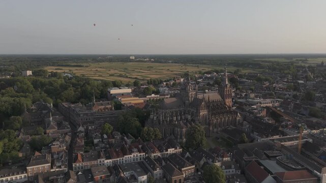 Aerial tilt-down view of St John's Cathedral in Den Bosch with hot air balloons