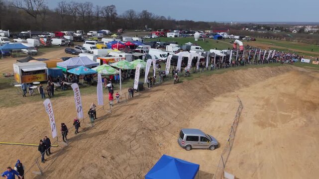 Aerial drone footage of motocross cross country race, dirt bikes speeding on rugged track, riders competing in off-road extreme motorsport event, dynamic action and dust clouds