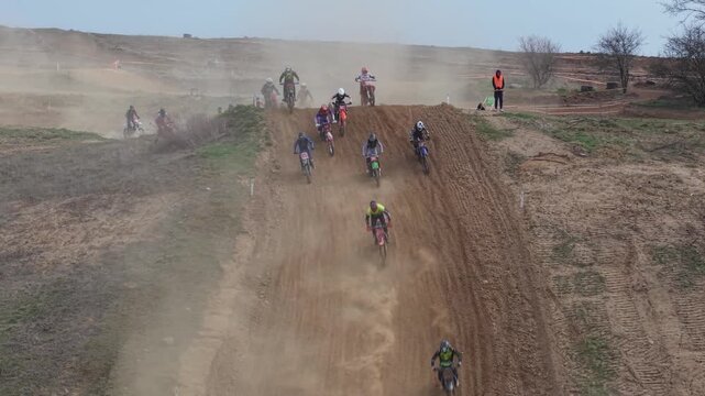 Aerial drone footage of motocross cross country race, dirt bikes speeding on rugged track, riders competing in off-road extreme motorsport event, dynamic action and dust clouds