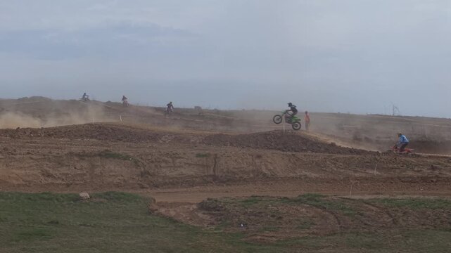 Aerial drone footage of motocross cross country race, dirt bikes speeding on rugged track, riders competing in off-road extreme motorsport event, dynamic action and dust clouds