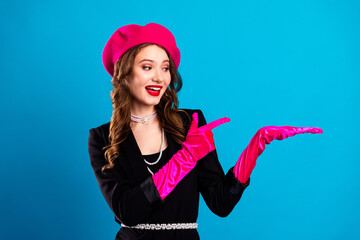 Chic Parisian woman in pink beret and gloves poses with confidence against a vibrant blue backdrop...