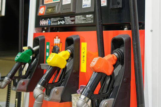 Gas station fuel nozzles for regular, high-octane and diesel in Japan, concept of rising fuel prices and household budget defense