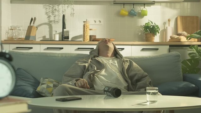 Man taking pills and leaning back on a couch, looking exhausted. Dependence of pills, medication overuse and stress