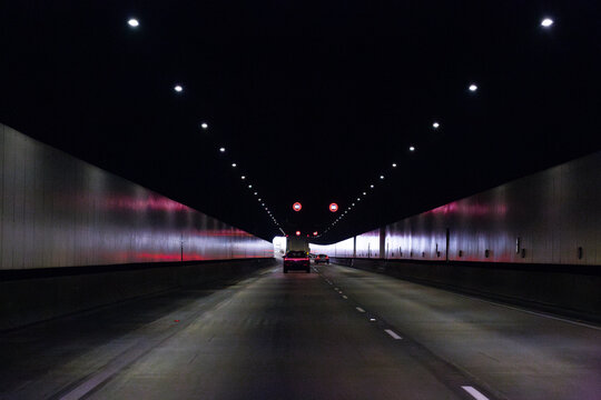Traffic on road cars and truck driving through tunnel under city with 80 speed limit signs