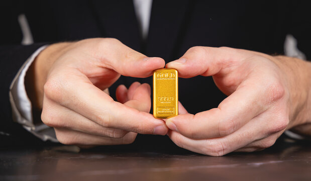 Gros plan sur une personne montrant un lingot d'or entre ses mains.
