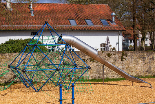 Children's playground with climbing frame and slide in bright daylight
