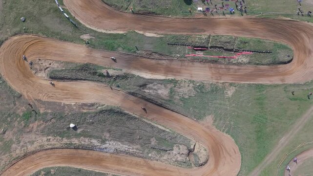 Aerial drone footage of motocross cross country race, dirt bikes speeding on rugged track, riders competing in off-road extreme motorsport event, dynamic action and dust clouds