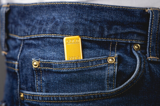 Gros plan sur un lingot d'or dans la poche d'un jean.