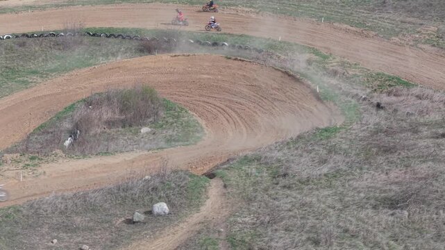 Aerial drone footage of motocross cross country race, dirt bikes speeding on rugged track, riders competing in off-road extreme motorsport event, dynamic action and dust clouds