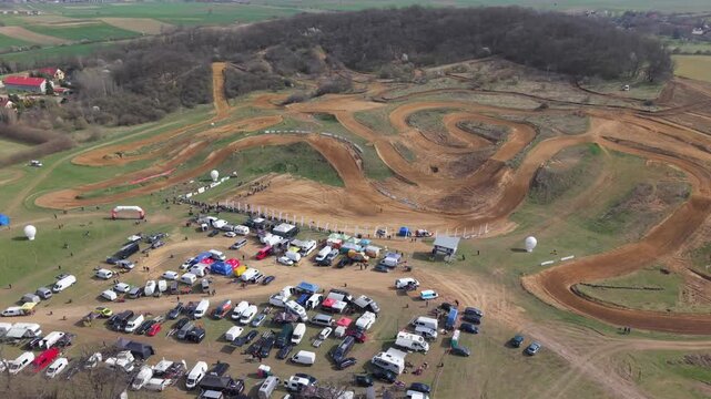 Aerial drone footage of motocross cross country race, dirt bikes speeding on rugged track, riders competing in off-road extreme motorsport event, dynamic action and dust clouds