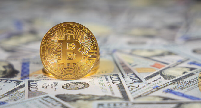Une pi&egrave;ce bitcoin dor&eacute;e, pos&eacute;e sur des billets en dollar, symbolisant les devises num&eacute;riques et papiers.
