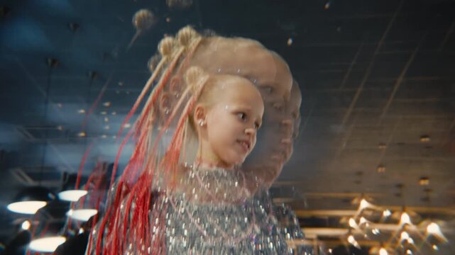 A young girl with red braids and a silver sequin dress dances energetically. A kaleidoscope prism effect creates a surreal, overlapping visual