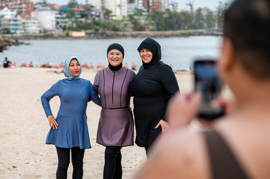 Women in burkinis striking a pose on the beach
