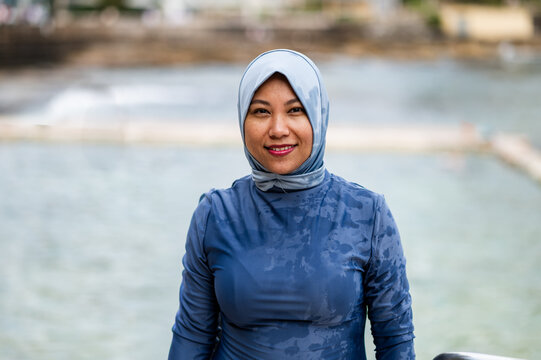 Portrait of a Filipina woman in a light blue headscarf standing in the ocean poolside