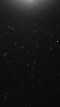 Vertical silver white glowing particles rising on black background with soft top light flare, 9:16 smartphone video, Full HD