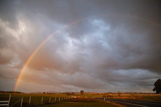 Vibrant rainbow arches over a rural landscape after a storm