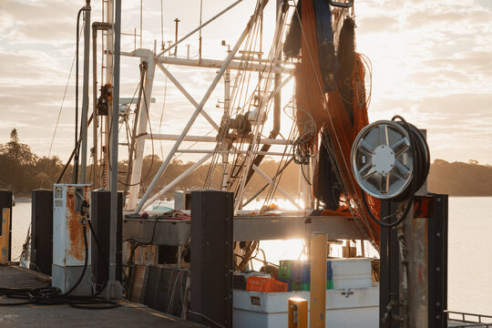 Fishing boat with equipment and nets docked at sunset with warm golden light