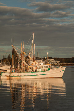 Fishing trawler docked at harbour with  golden hour reflections on water