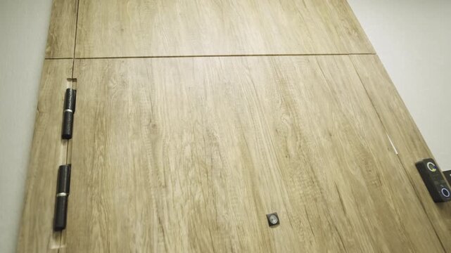 Modern apartment door with peephole and number sign nearby on wall closeup. Protected entrance to private residence in building hall