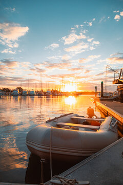 Golden sunset over a marina with a small inflatable boat docked by the pier
