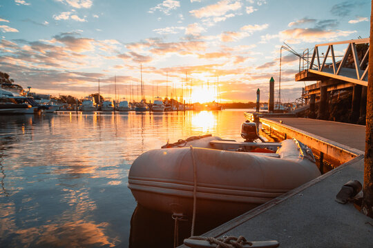 Golden sunset over a marina with boats docked and an inflatable dinghy