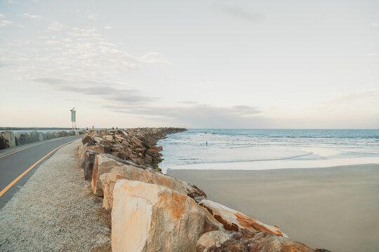 Scenic coastal pathway curves alongside a rocky breakwater with the ocean stretching to the horizon