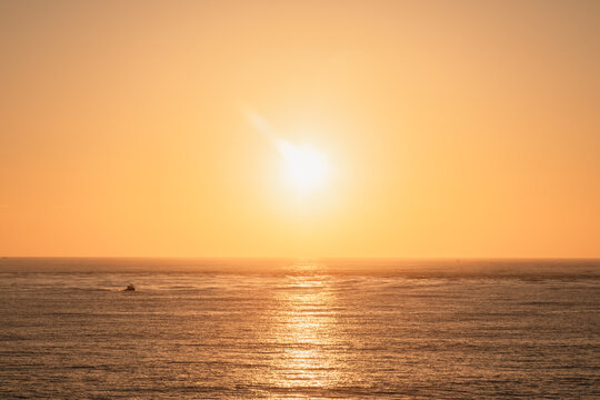 Golden sunrise over the ocean on the east coast of Australia with a small boat sailing on the water