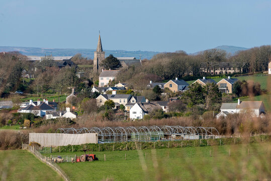 Bigbury South Hams Devon UK. 21.03.2026. A charming rural village scene unfolds with diverse architecture and lush green fields under a clear blue sky