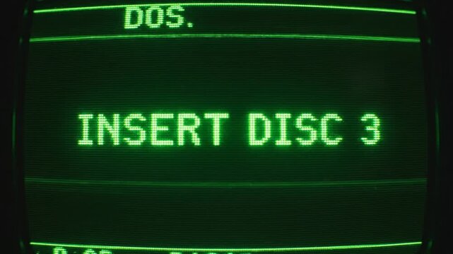 Close-up. Old computer terminal displaying green 'INSERT DISC 3' prompt on monochrome CRT. Scanlines. Vintage computing.