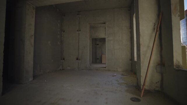 Empty enclosures with concrete walls inside incomplete building. Observing multistory residential house construction site in urban district