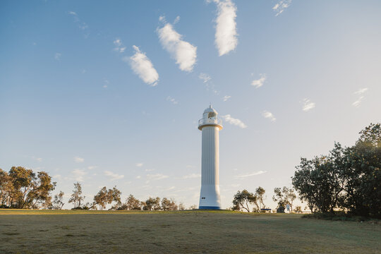 White lighthouse standing tall against a clear blue sky with scattered clouds