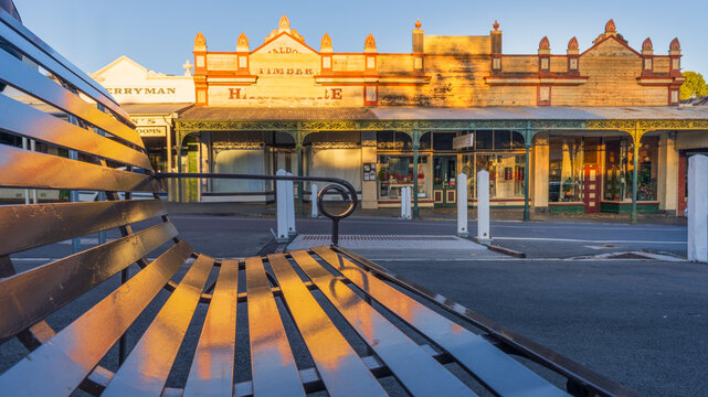 Low angle view of a street bench reflecting an historic building facade bathed in golden light
