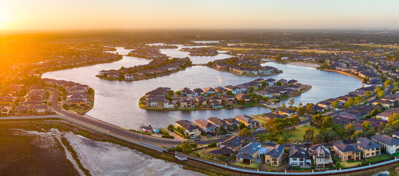 Aerial panorama view a large housing estate around manmade lakes at sunet