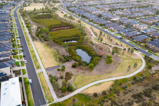 Aerial view of ponds in an urban parkland bordered by roads on housing