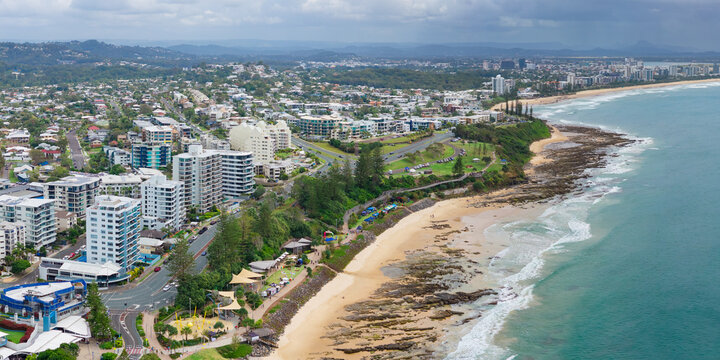 Aerial view of dark clouds building over a rocky coastline and waterfront buildings