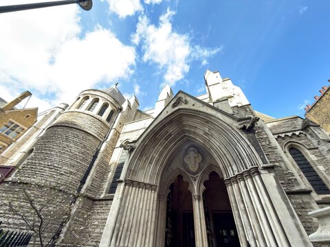 Gothic Church Portals: The intimidating and ornate wooden doors of a Gothic church set against a clear blue sky with dramatic white clouds.