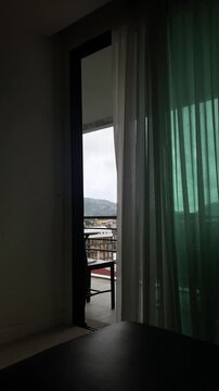 Open balcony door with view of city skyline from a hotel room, travel lifestyle and urban escape concept.