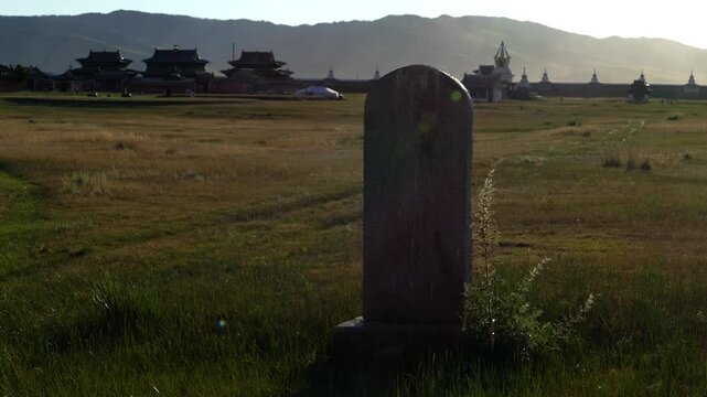 Stone stele on the background of silhouettes of temples and walls of the ancient Buddhist monastery of Erdene Zuu, Kharkhorin, Mongolia. The stupa is a sacred Buddhist structures. Sunny summer evening