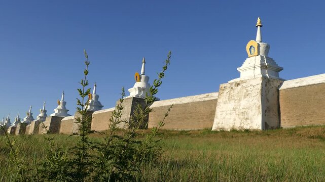Rocky wall and stupas of the ancient Buddhist monastery of Erdene Zuu against the blue sky. Kharkhorin, Mongolia. The stupa is a sacred Buddhist structures. Sunny summer evening.
